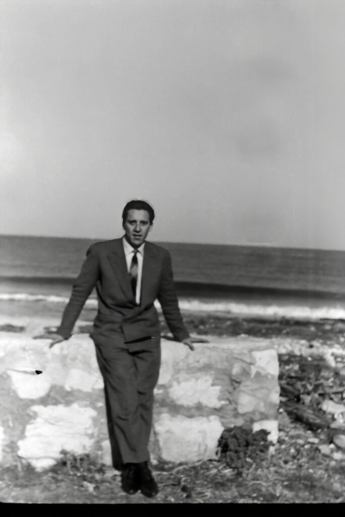 Mio padre Giancarlo in giacca e cravatta appoggiato a un muretto davanti al mare